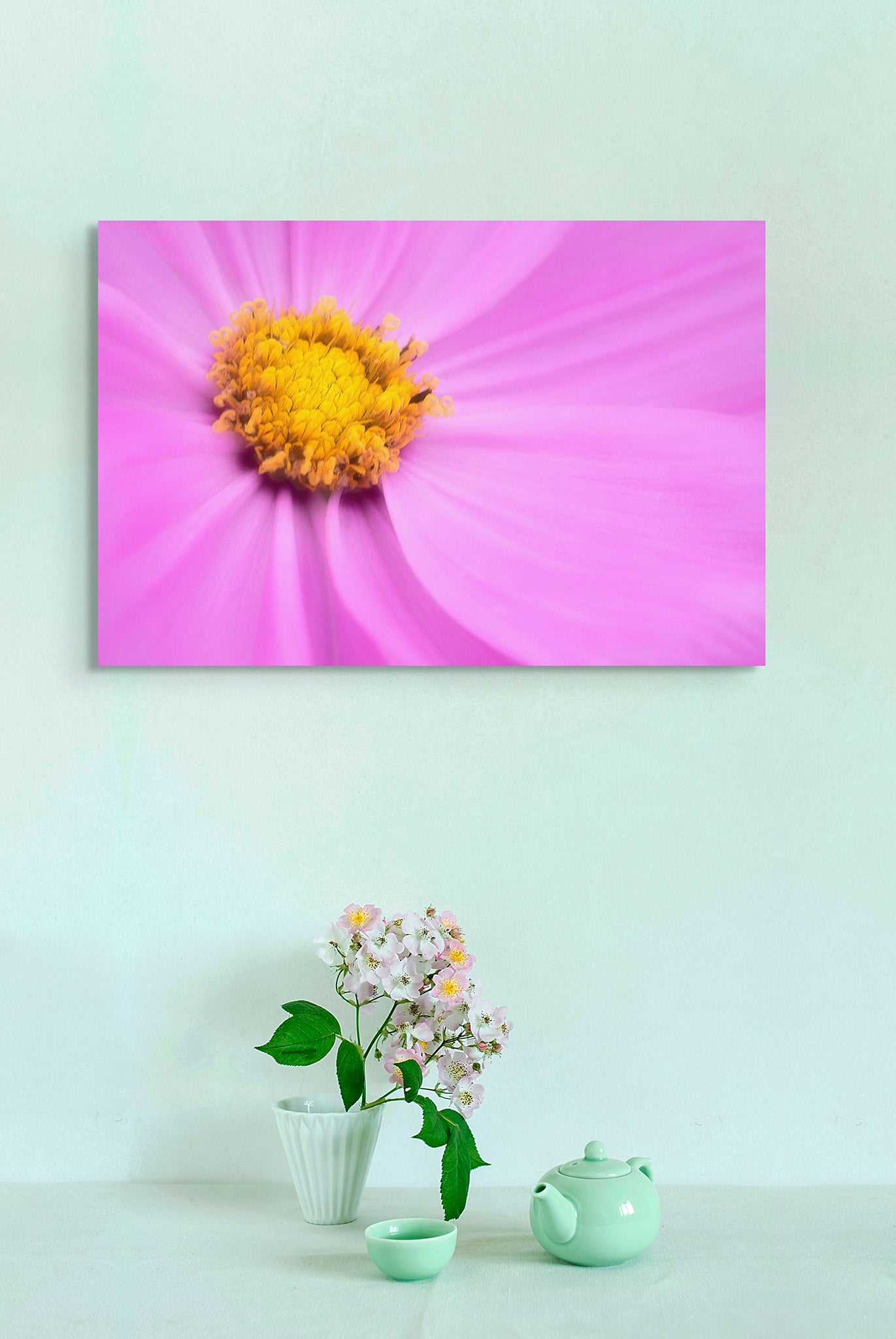 Picture hanging on a green wall. The picture is a macro photograph of purple cosmopolitan flower by Cameron Dreaux. 