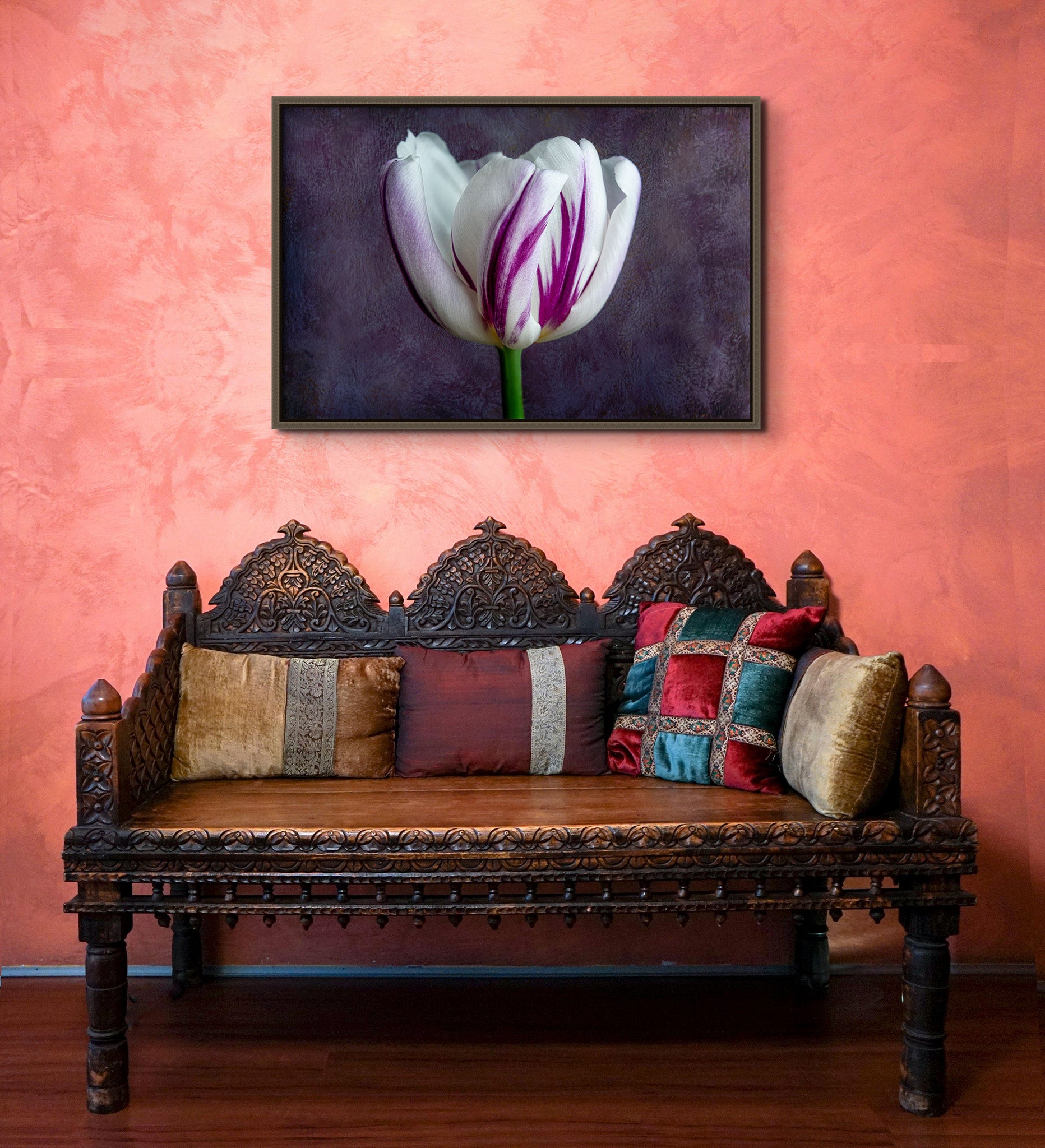Picture hanging in an orange room over a metal bench. The picture is a fine art flower photograph of a single tulip titled "Audrey" by Cameron Dreaux of Dreaux Fine Art. 