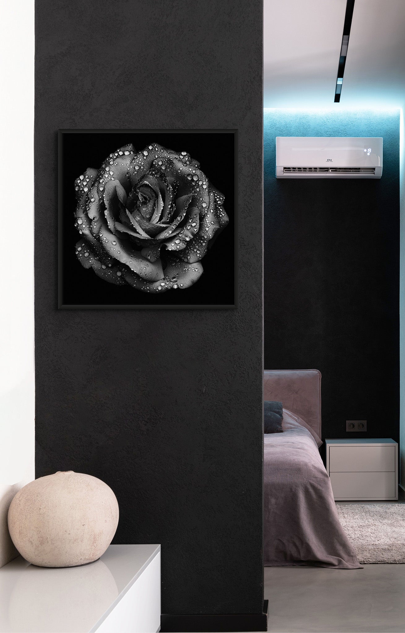 Picture hanging on the wall of a bedroom. The picture is a black and white fine art photograph of a rose by Cameron Dreaux. 
