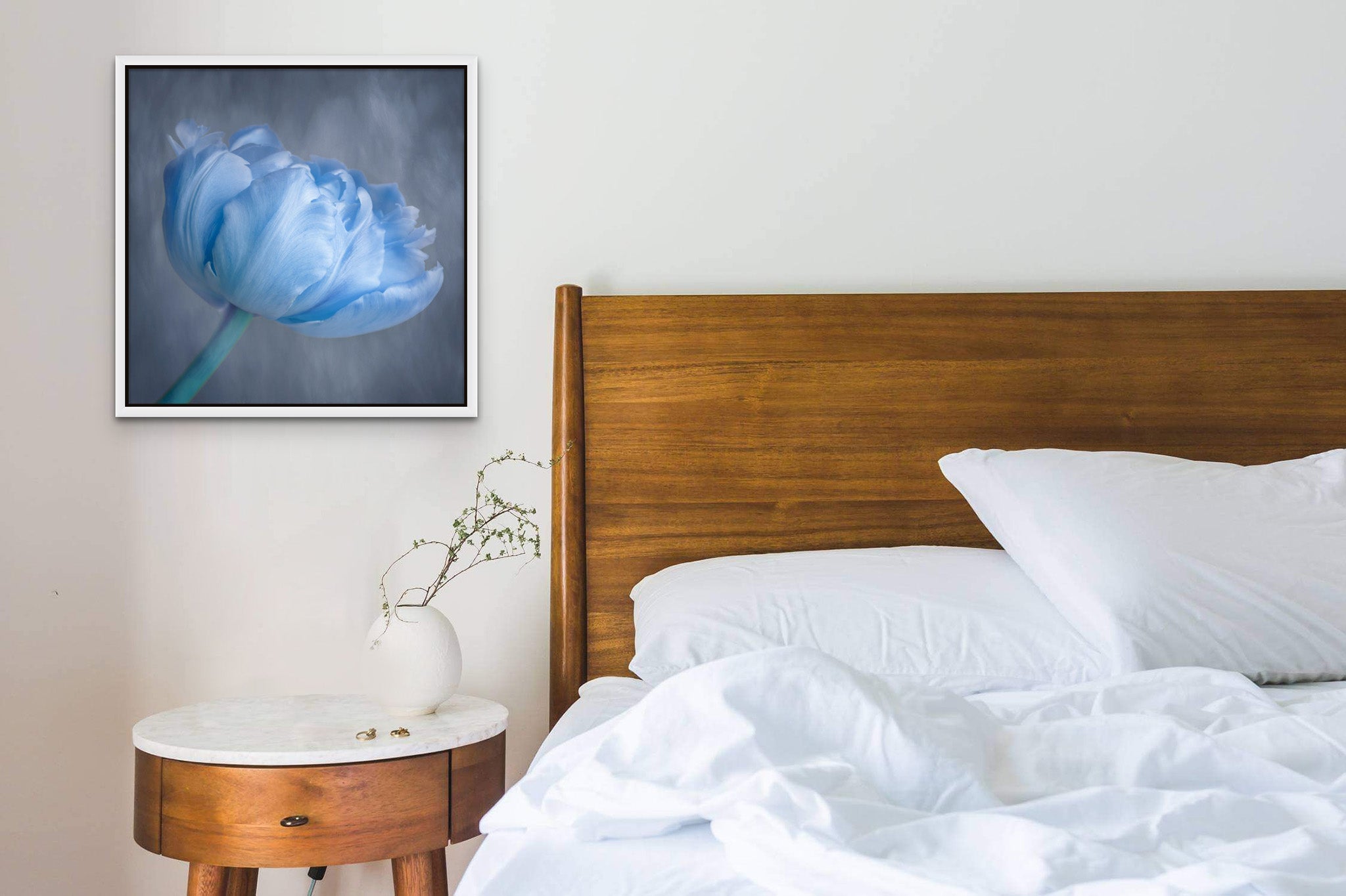 Picture hanging on the wall of a bedroom. The picture is a fine art photograph of a blue tulip by Cameron Dreaux. 