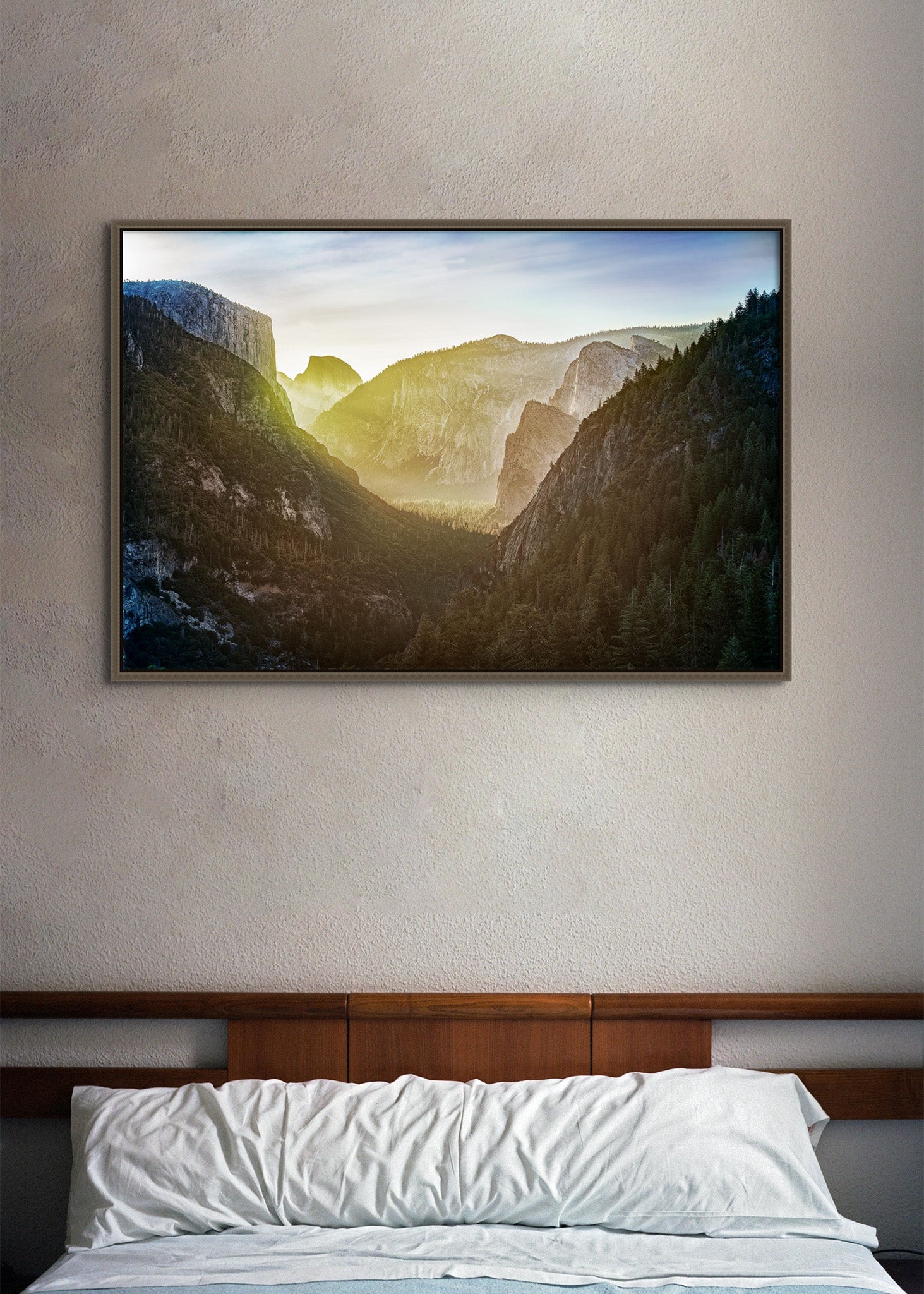 Picture hanging on the wall of a hotel bed. The picture is a fine art landscape photograph titled "The Valley Awakens" by Cameron Dreaux of Dreaux Fine Art.