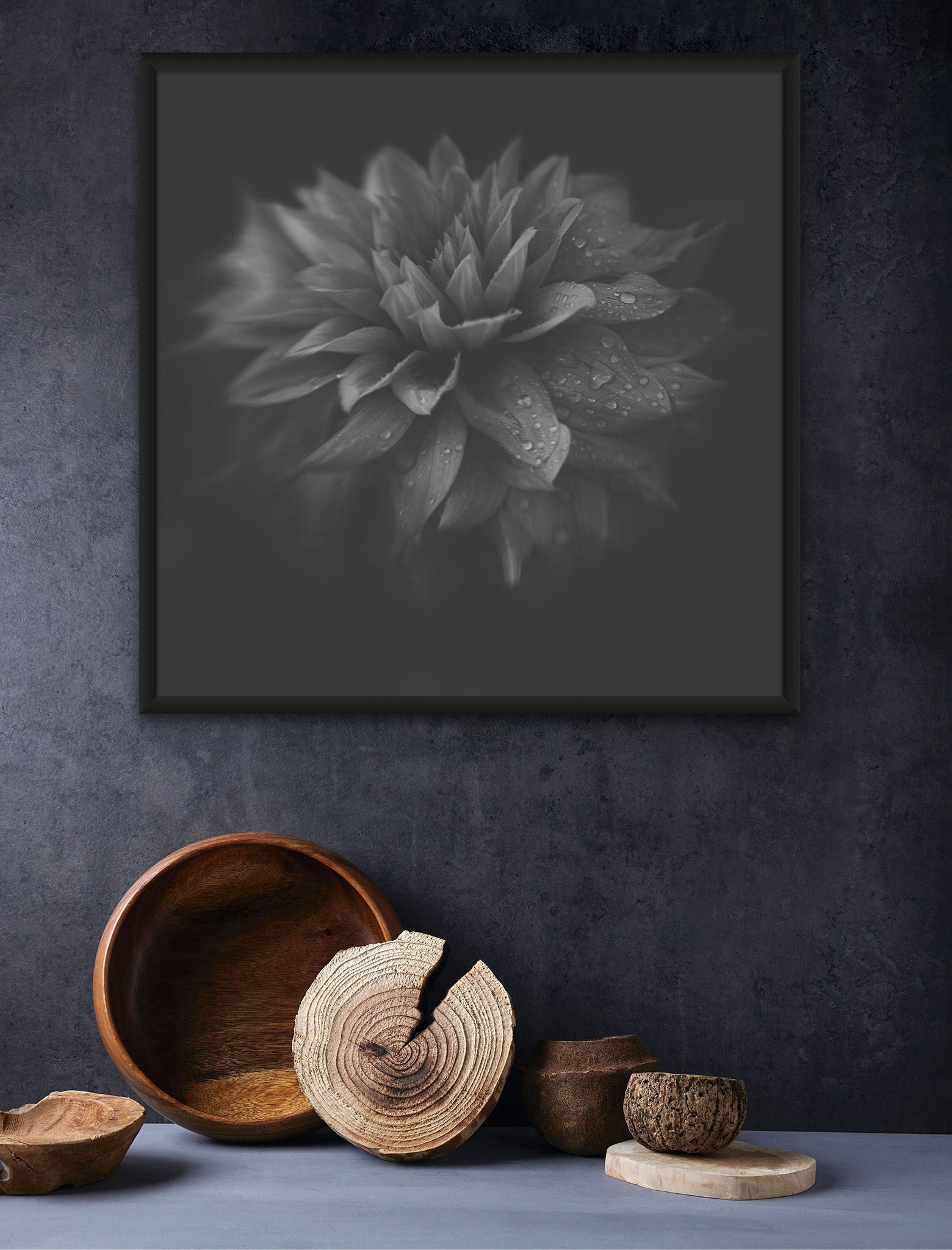 Picture on the wall of a room. There is several woven pots on the floor. The picture on the wall is a black and white macro photograph of Dahlia by Cameron Dreaux. 