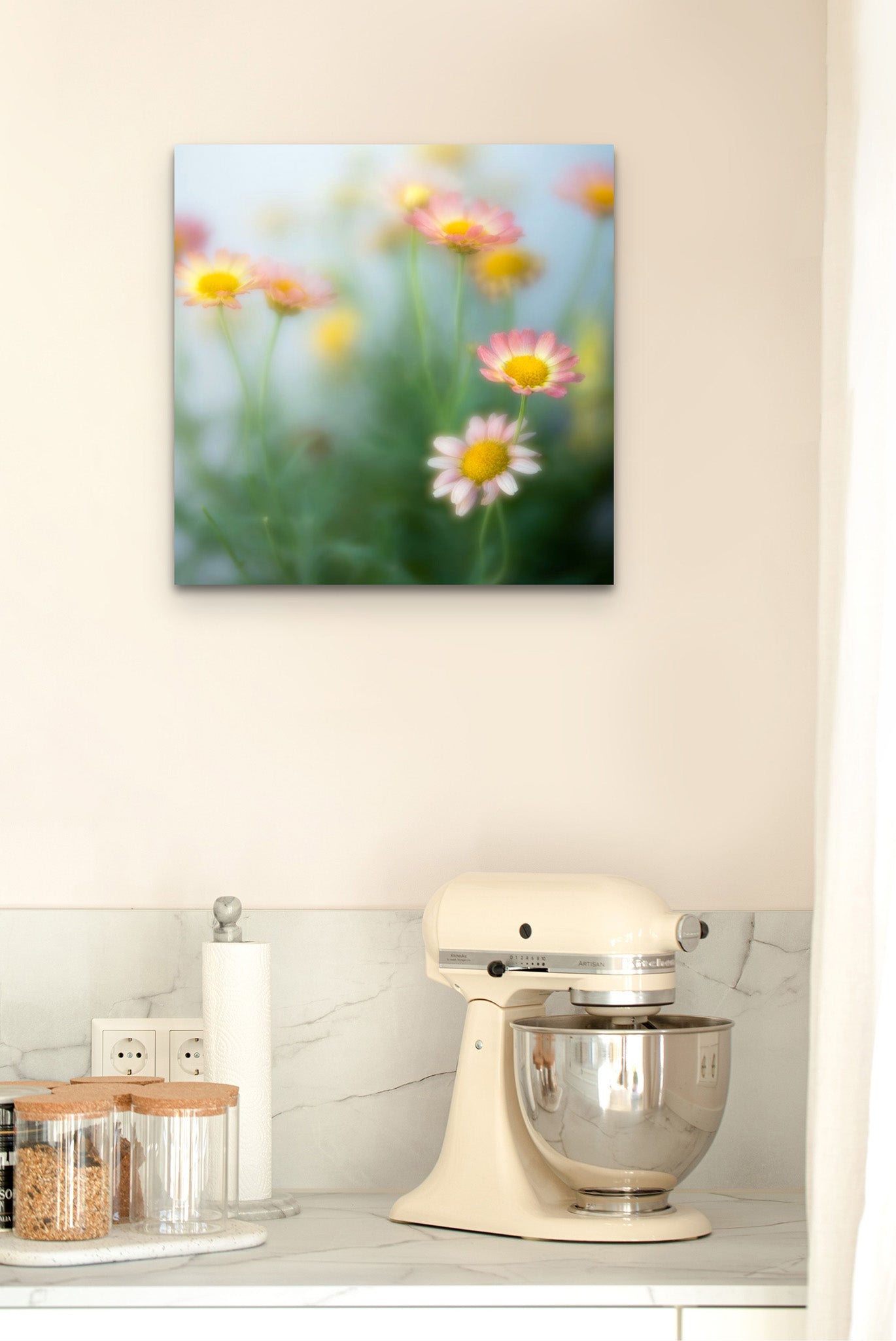 Wall in a kitchen and countertop. On the countertop, there is a stand mixer. On the wall hangs a metal print. The print hanging on the wall is a fine art photograph of pastel flowers by Cameron Dreaux. 