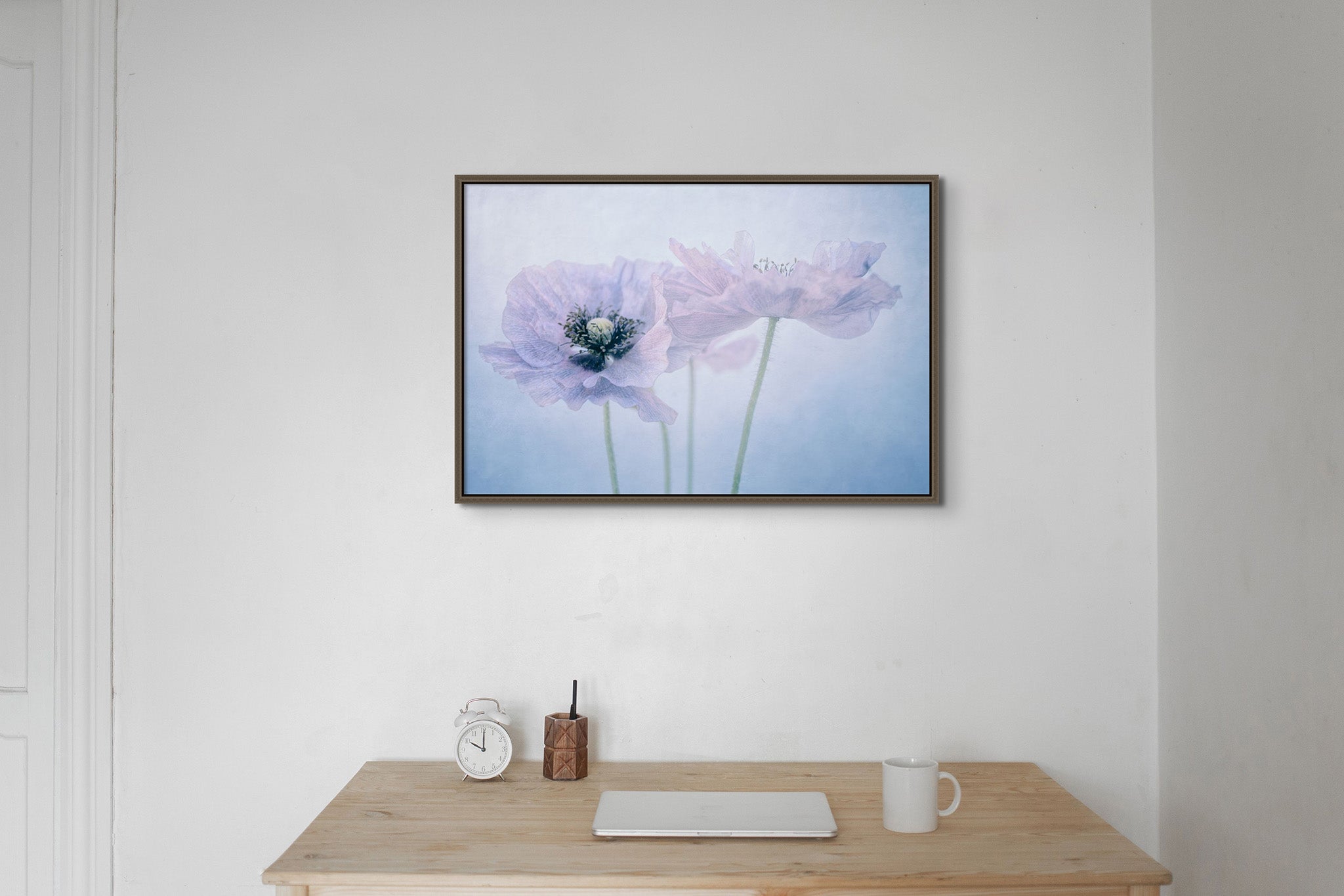 A picture on wall over a desk.  The picture is a fine art flower photograph by Cameron Dreaux. of 3 pastel-colored poppies. 