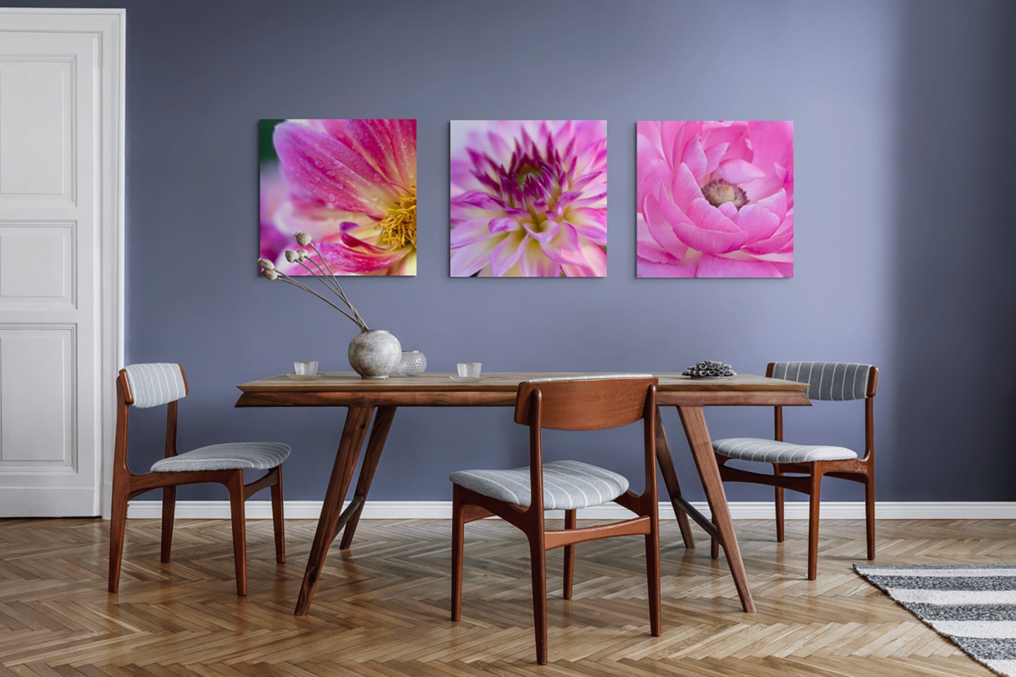 Three pictures on the wall of a dining room with a set table.. The pictures are all metal print macro fine art photographs of dahlia flowers by artist Cameron Dreaux. 