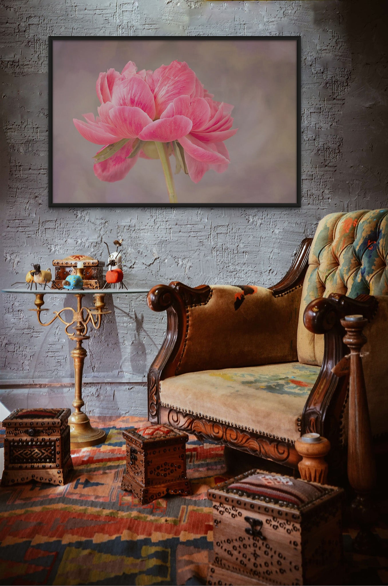 Picture hanging on the wall of a room with a chair. The photograph is in a float frame. The photography is a fine art Metal print of pink Peony with the petals blowing in the wind. The photograph is by Cameron Dreaux. 