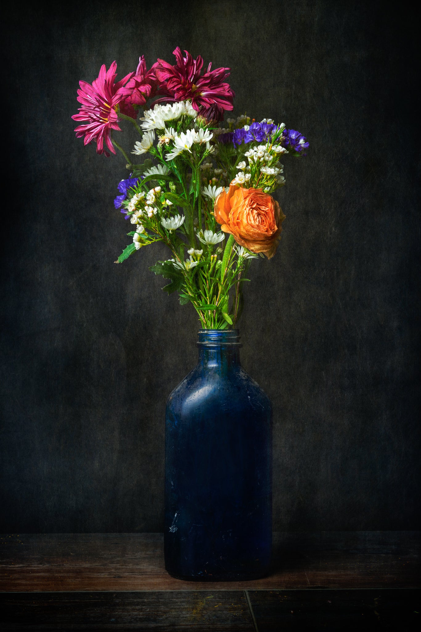 Fine art flower photograph of a bouquet of flowers in an old bottle titled "Tangy Resolve" by Cameron Dreaux of Dreaux Fine Art.