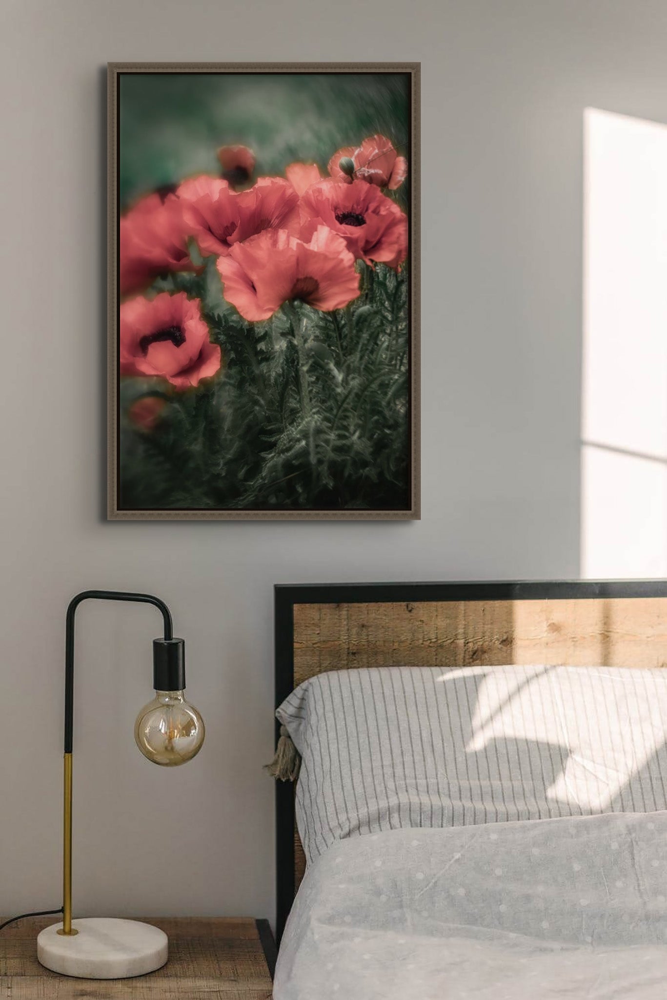 Picture in a floating frame hanging on the wall of a bedroom. The picture is a fine art photograph of red poppies on dark green stormy background by Cameron Dreaux. 
